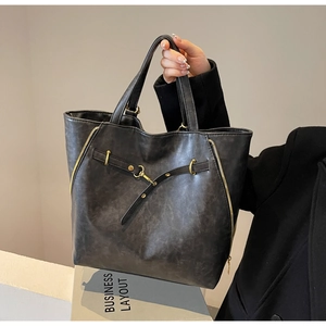 Detailed close-up of retro charcoal faux leather tote bag with metallic buckle and gold zippers
