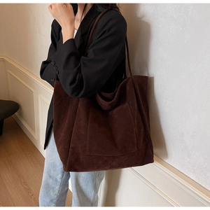 Detail showing high-capacity suede tote bag in dark brown with a front patch pocket