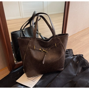 Detail view of large vintage brown leather tote bag with gold buckle and side zippers