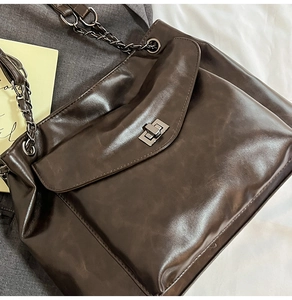 Dettaglio della borsa tote marrone cioccolato con chiusura a scatto e tracolla a catena