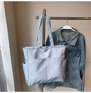 Détail du sac cabas en nylon bleu clair avec poches extérieures et longues lanières