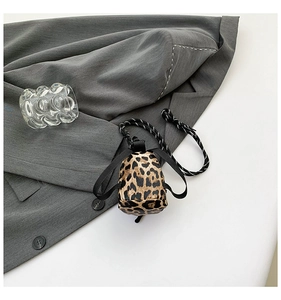 Macro shot of mini leopard print bag with woven lanyard on a grey fabric backdrop