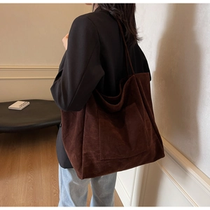 Detail of a brown suede large capacity tote bag with long shoulder strap and front pocket