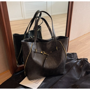 Detailed macro view of black faux leather tote bag with gold zippers and metal hardware