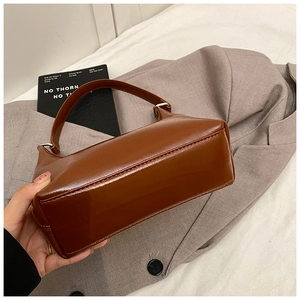 Dettaglio borsa a mano marrone in pelle PU lucida con cuciture e manico ad anello metallico