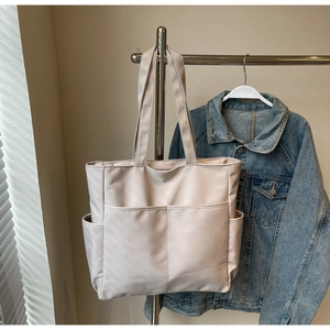 Vue détaillée du grand sac cabas beige en toile avec poches pratiques pour le bureau