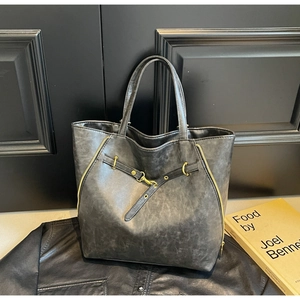 Detail of vintage large charcoal tote bag with golden zippers and leather strap buckle