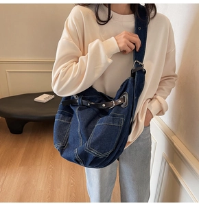 Detailansicht der großen Denim-Umhängetasche mit Lederriemen und Metallschnallen