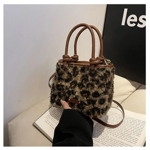 Détail du sac seau léopard en fausse fourrure avec poignée nouée en cuir et logo métallique