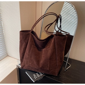 Macro detail of dark brown suede tote bag featuring fine stitching and smooth matte texture