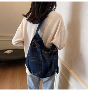 Detail der großen Denim-Umhängetasche mit verstellbaren Lederriemen an der Schulter