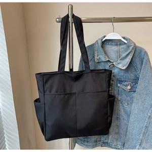 Gros plan du sac fourre-tout en nylon noir avec poches avant et compartiments latéraux