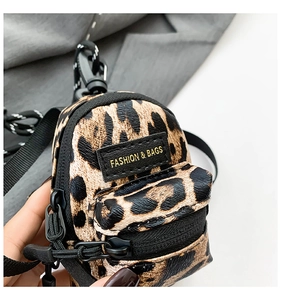 Macro detail of mini leopard print charm bag with zipper texture and metal hook