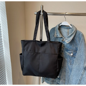Détail du grand sac cabas noir en toile avec poches avant et rangement latéral pratique