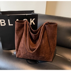 Detail of deep brown suede tote bag with large front pocket and slim shoulder straps