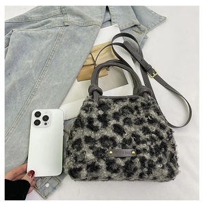 Dettaglio borsa a secchiello in peluche leopardata con manici in pelle su sfondo lifestyle