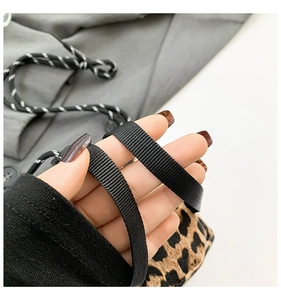 Close-up of the leopard print fabric texture and durable black nylon shoulder strap