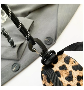 Close-up of leopard print mini bag featuring a black lobster clasp and braided lanyard strap