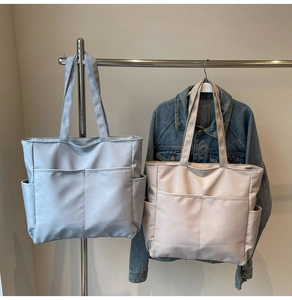 Détail montrant des sacs cabas en toile bleu clair et beige avec poches latérales