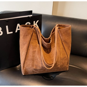 Macro detail of brown suede tote bag featuring minimalist pocket and fine stitching