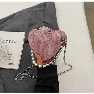 Dettaglio della borsa a cuore in denim rosa con tracolla di perle e zip in argento