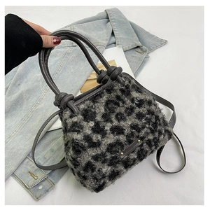 Dettaglio della borsa a secchiello in peluche leopardato con manici in pelle grigia e logo