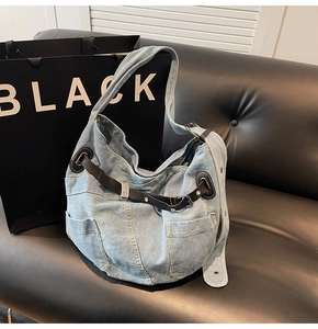 Detail der hellblauen Denim-Hobo-Tasche mit schwarzen Lederriemen und Seitentaschen