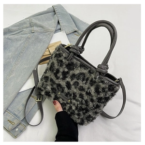 Dettaglio borsa leopardata in ecopelliccia con logo dorato e manico in pelle grigia