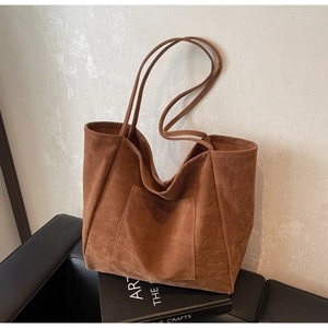 Close-up of brown suede tote bag featuring a front patch pocket and long shoulder straps
