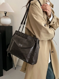 Grande borsa tote vintage marrone scuro con catena indossata con un trench beige