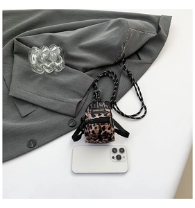 Detailed view of mini leopard print backpack charm with metal carabiner and woven cord