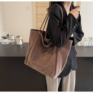 Brown suede tote bag with large capacity and shoulder strap shown on a model