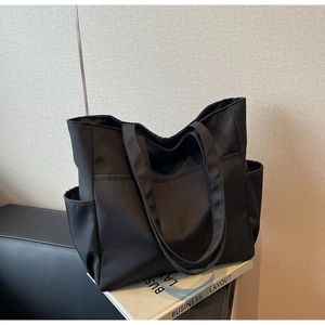 Vue détaillée du grand sac fourre-tout noir en nylon avec poignées et poches latérales