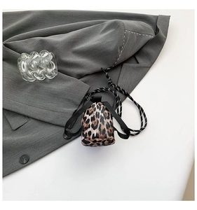 Detailed view of mini leopard print crossbody bag on a gray suit jacket background