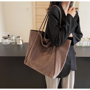 Close-up of brown suede tote bag with large front pocket and slim shoulder strap