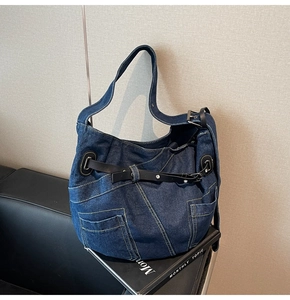 Detail der blauen Denim-Hobo-Tasche mit silbernen Ösen und schwarzen Leder-Gürtelschnallen