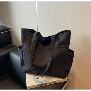 Détail de la poche latérale ouverte et texture en nylon du grand sac cabas noir