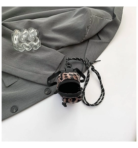 Close-up of mini leopard print crossbody bag with woven strap on grey suit fabric