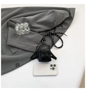 Micro mini black crossbody bag in lychee pattern PU leather next to a smartphone
