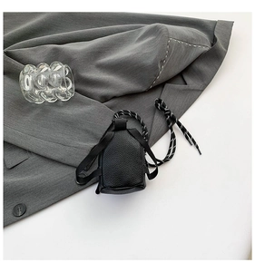 Close-up of mini black lychee texture crossbody bag with striped rope detail