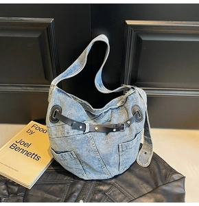 Detail der blauen gewaschenen Denim-Tasche mit schwarzen Lederriemen und Metallschnallen
