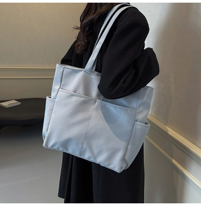 Détail du grand sac cabas bleu clair avec plusieurs poches et des bretelles fines