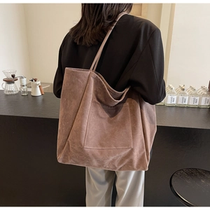 Close-up of brown faux suede tote bag with front pocket and long shoulder straps