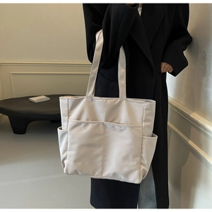Détails du grand sac cabas en toile crème avec plusieurs poches extérieures et anses doubles