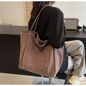 Close-up of a large coffee brown suede tote bag featuring a front pocket and long straps