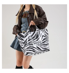 Close-up of zebra print tote bag with white TOTE BAG text carried by model