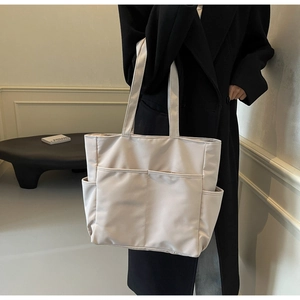 Vue détaillée du sac cabas en toile blanc cassé avec plusieurs poches utilitaires pratiques