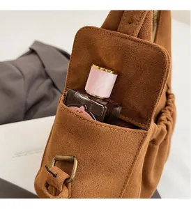 Detailed close-up of brown suede tote bag featuring a front pocket and vintage metal buckle