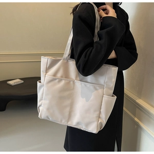 Détail du cabas en toile beige clair avec grandes poches avant et large bandoulière