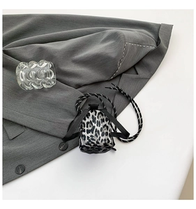 Close-up of trendy leopard print mini crossbody bag for girls with woven strap and stylish texture